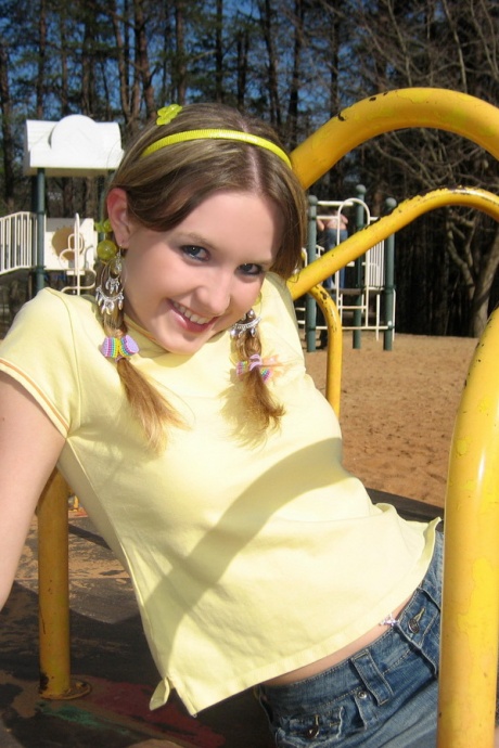 Симпатичная девушка обнажает свой лифчик и трусики под юбкой на детской площадке 3