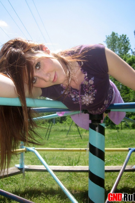Молодая рыжеволосая красотка демонстрирует свою грудь и трусики на детской площадке 10