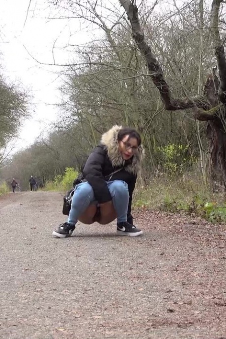 Девушка-одиночка Наташа Инк садится на корточки, чтобы пописать, на проселочной дороге, одетая в парку 3