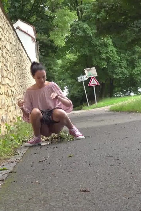 Коротко снятая девушка Мистика садится на корточки, чтобы пописать, на мощеной дорожке в городской обстановке 12